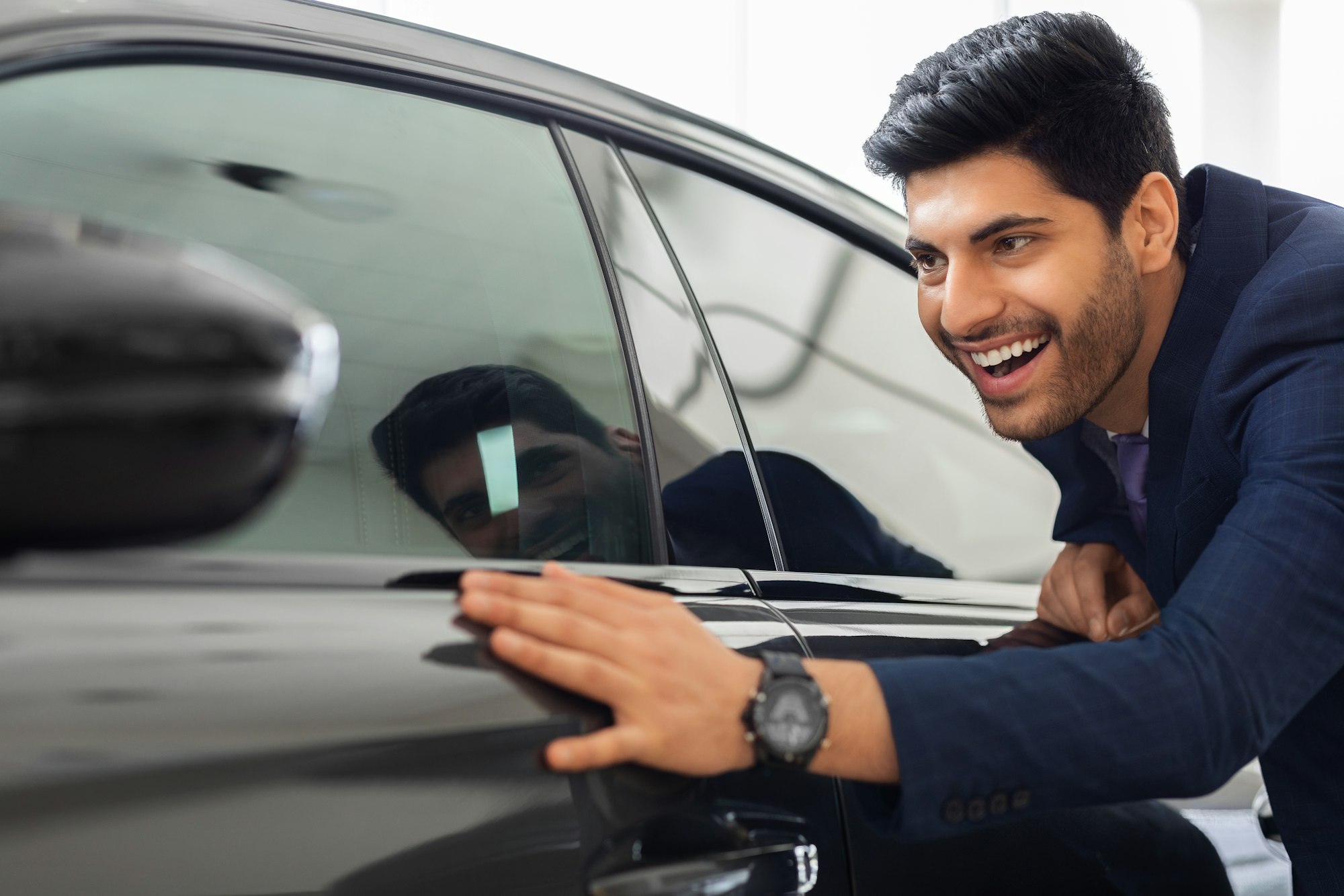 Excited middle-eastern businessman touching brand new car